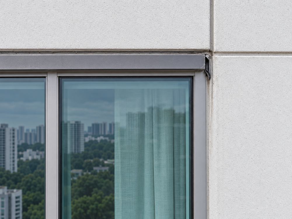 Close-up of a window frame corner where the sealant and gasket have failed